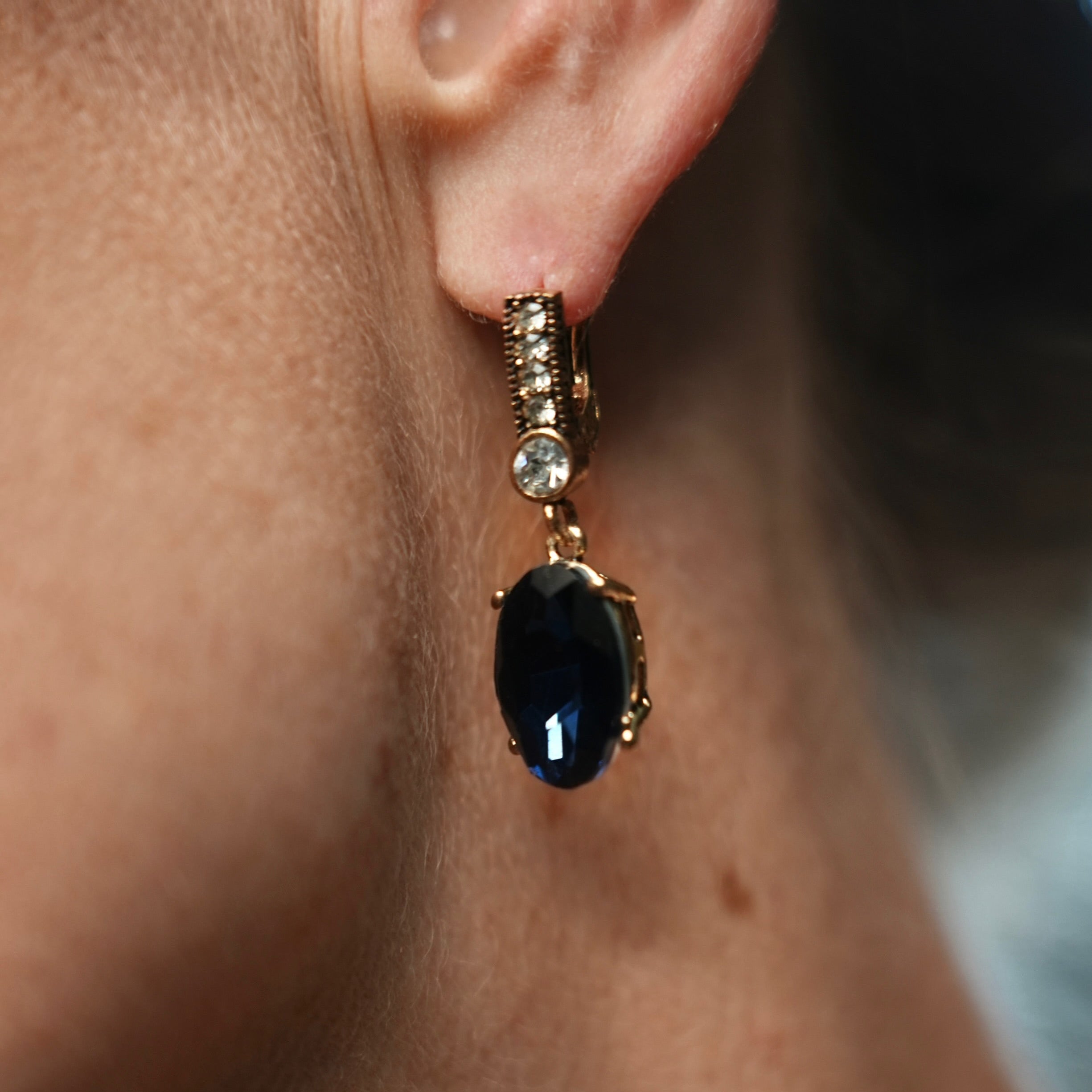 Close-up of an earring with a black gemstone on a person's ear.
