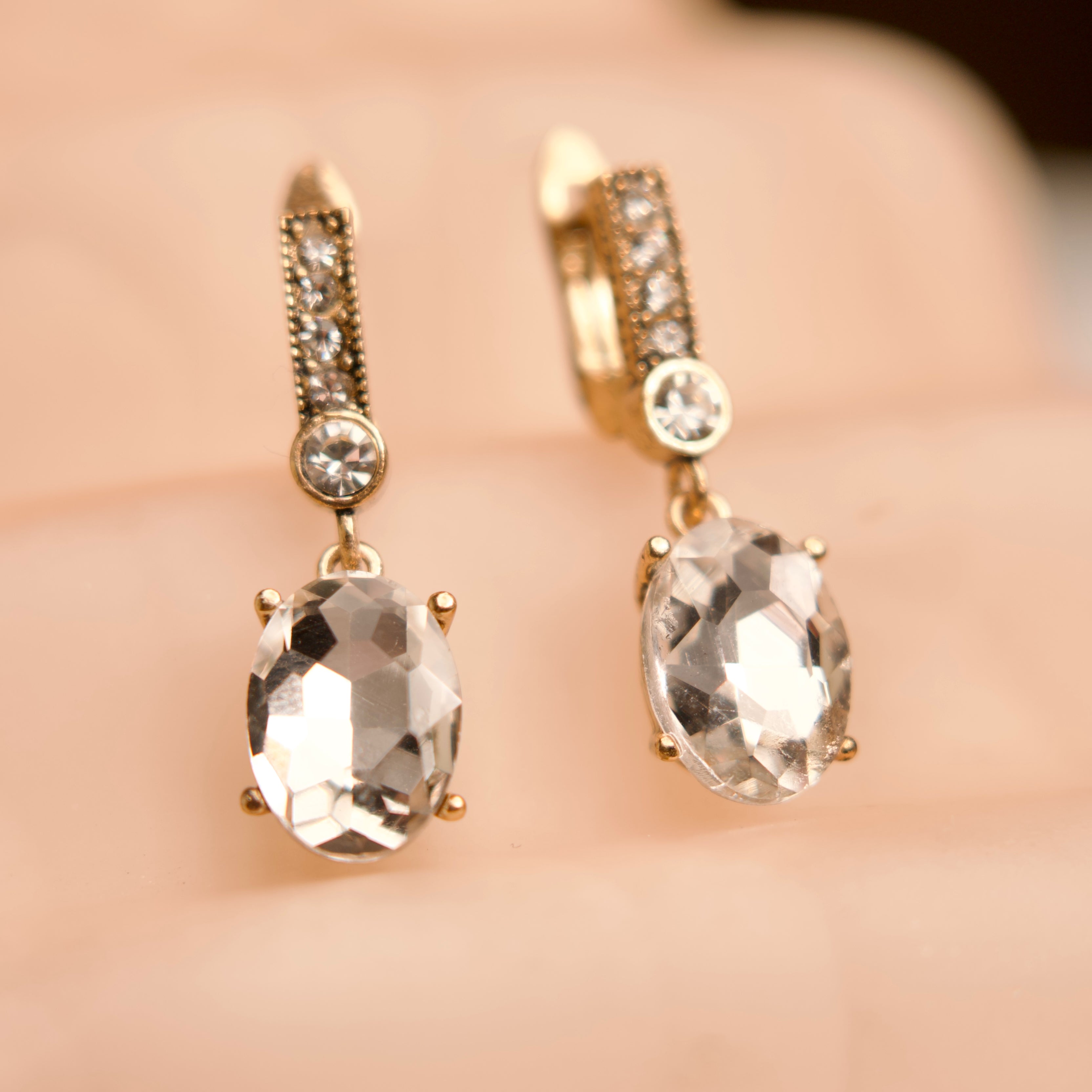 Gold earrings with clear gemstones on a blurred background