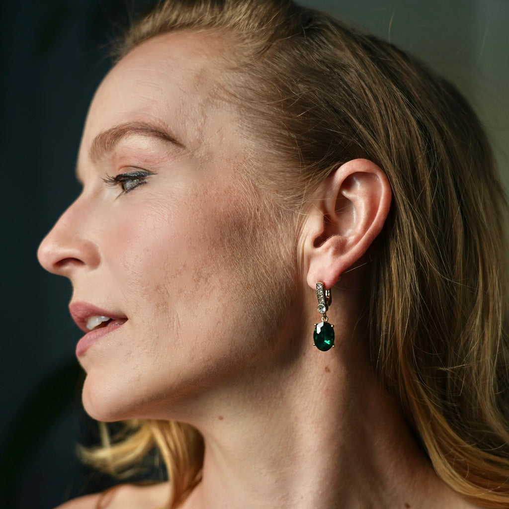 Close-up of a woman wearing earrings and a ring with a dark background