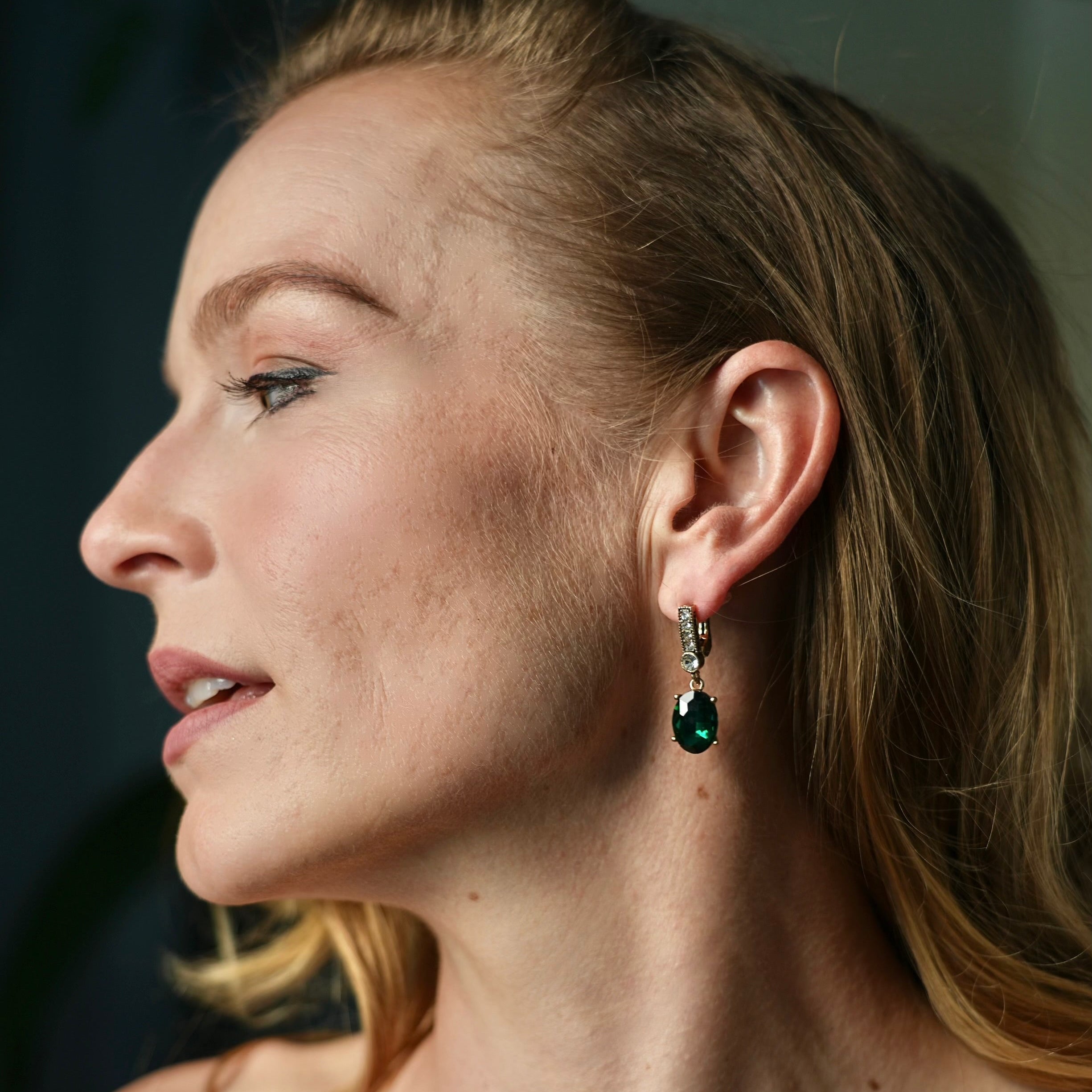 Close-up of a woman wearing earrings and a ring with a dark background