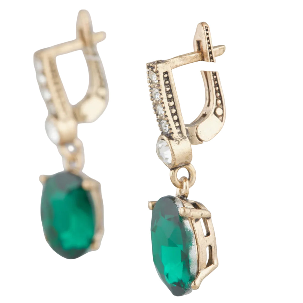 Gold earrings with green gemstones on a white background
