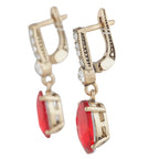 Gold earrings with red gemstones on a white background