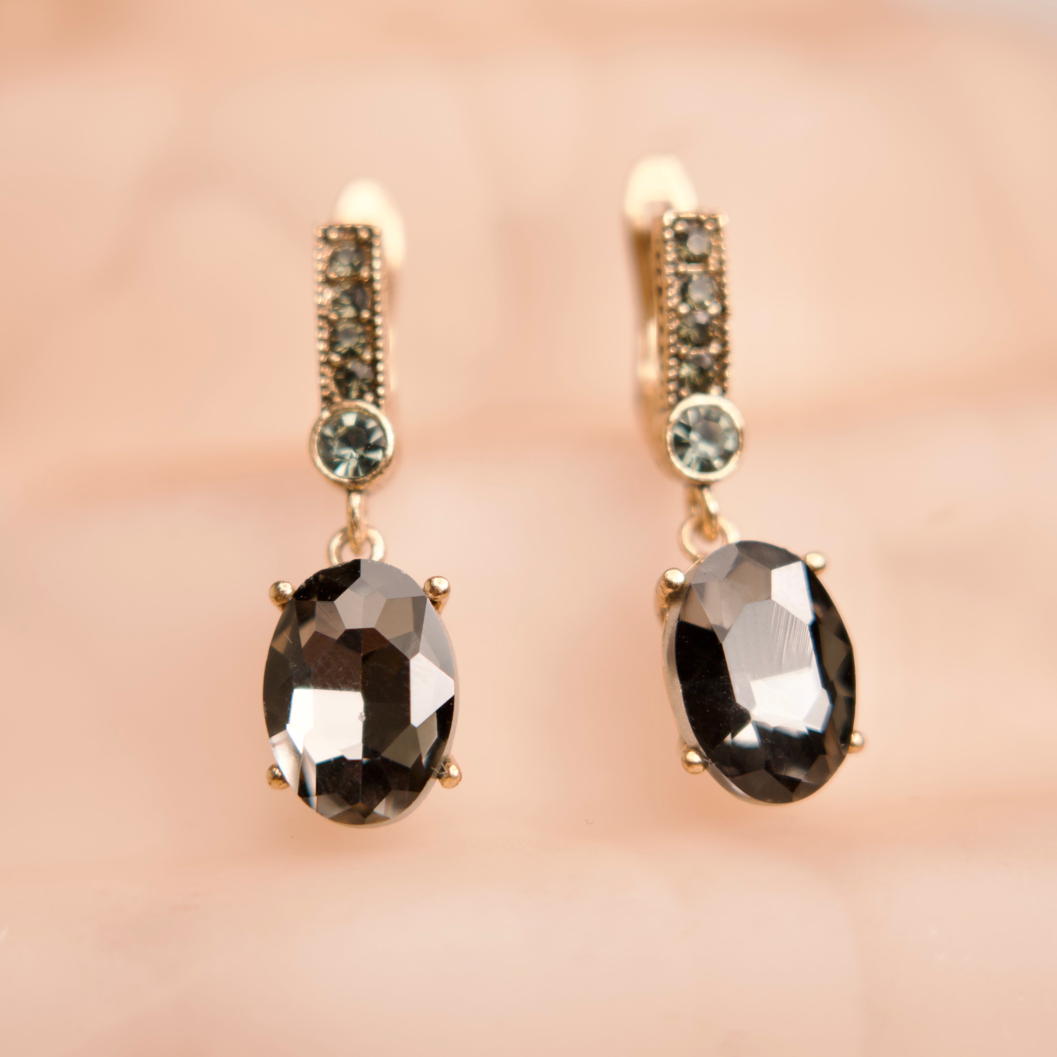 Pair of earrings with smoky gemstones on a soft pink background