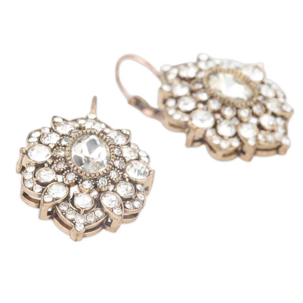 Pair of ornate earrings with clear gemstones on a white background