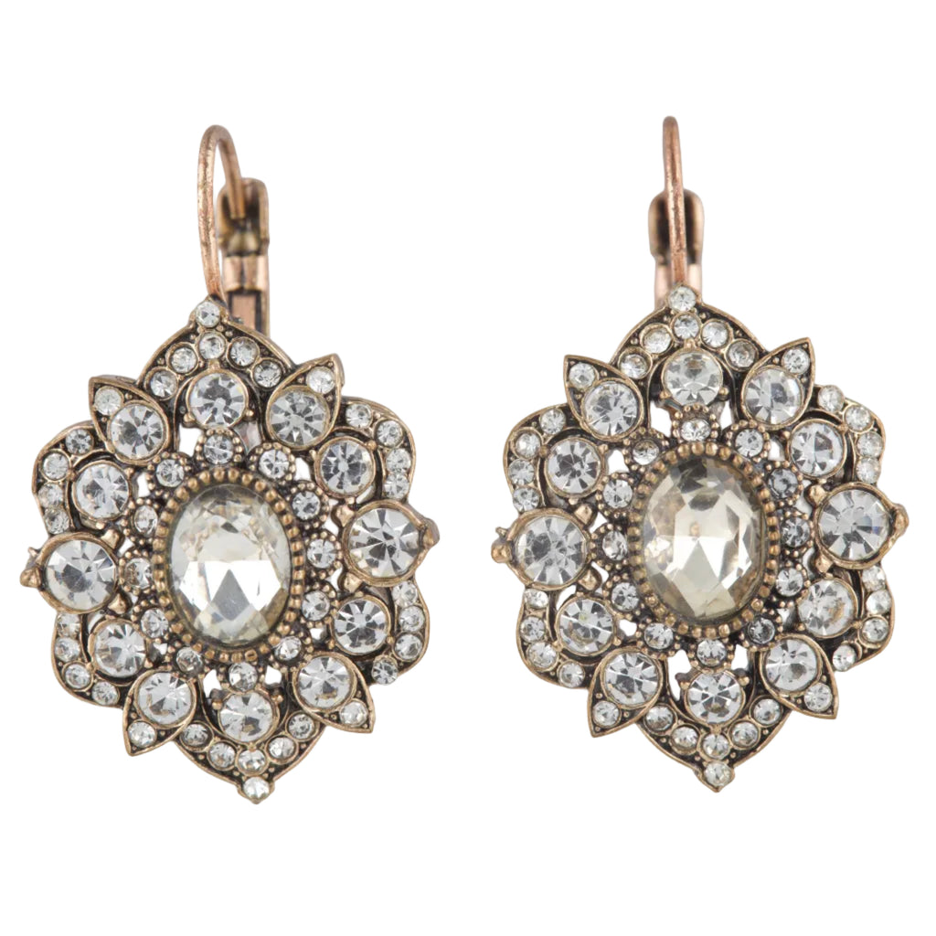 Pair of ornate earrings with clear gemstones on a white background