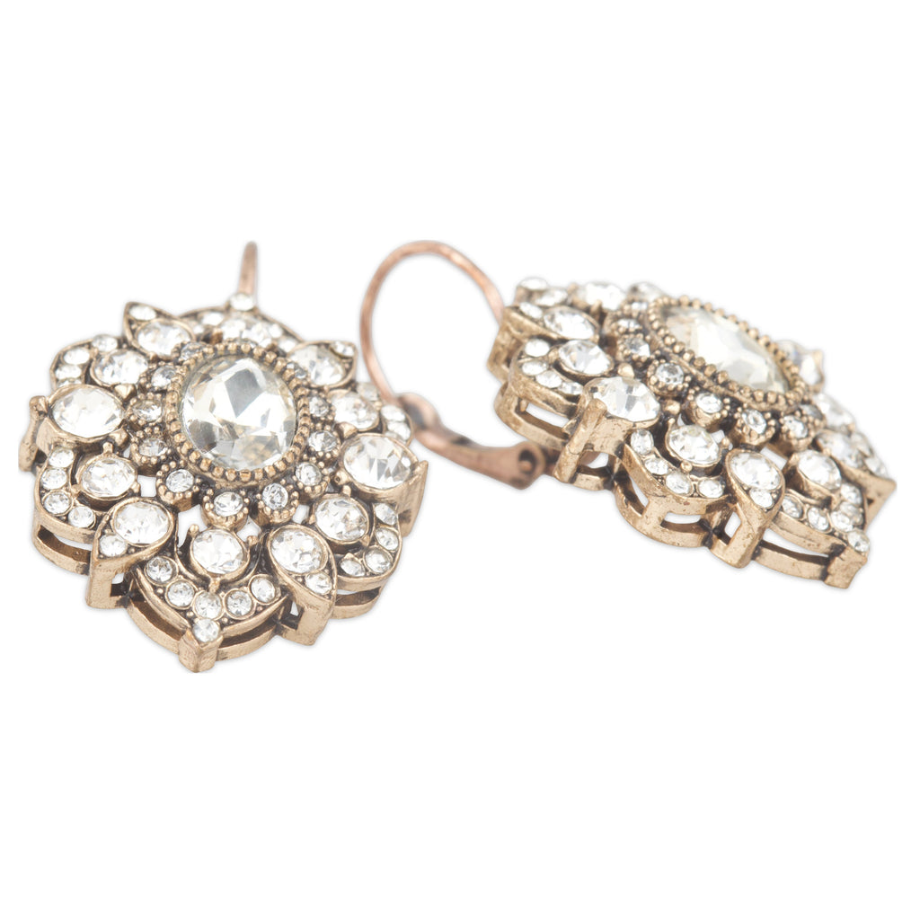 Pair of ornate earrings with clear gemstones on a white background