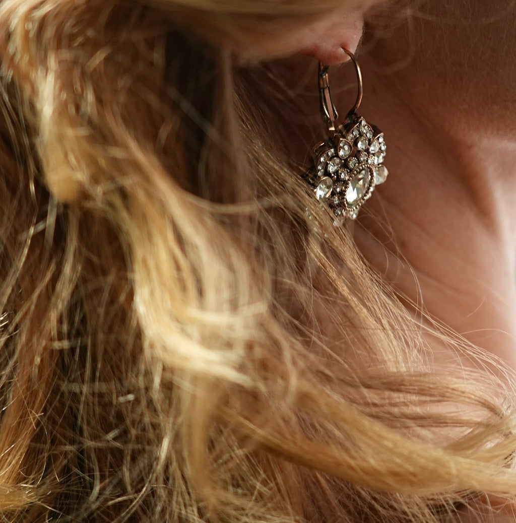 Close-up of a woman with styled hair and an earring, with a blurred background