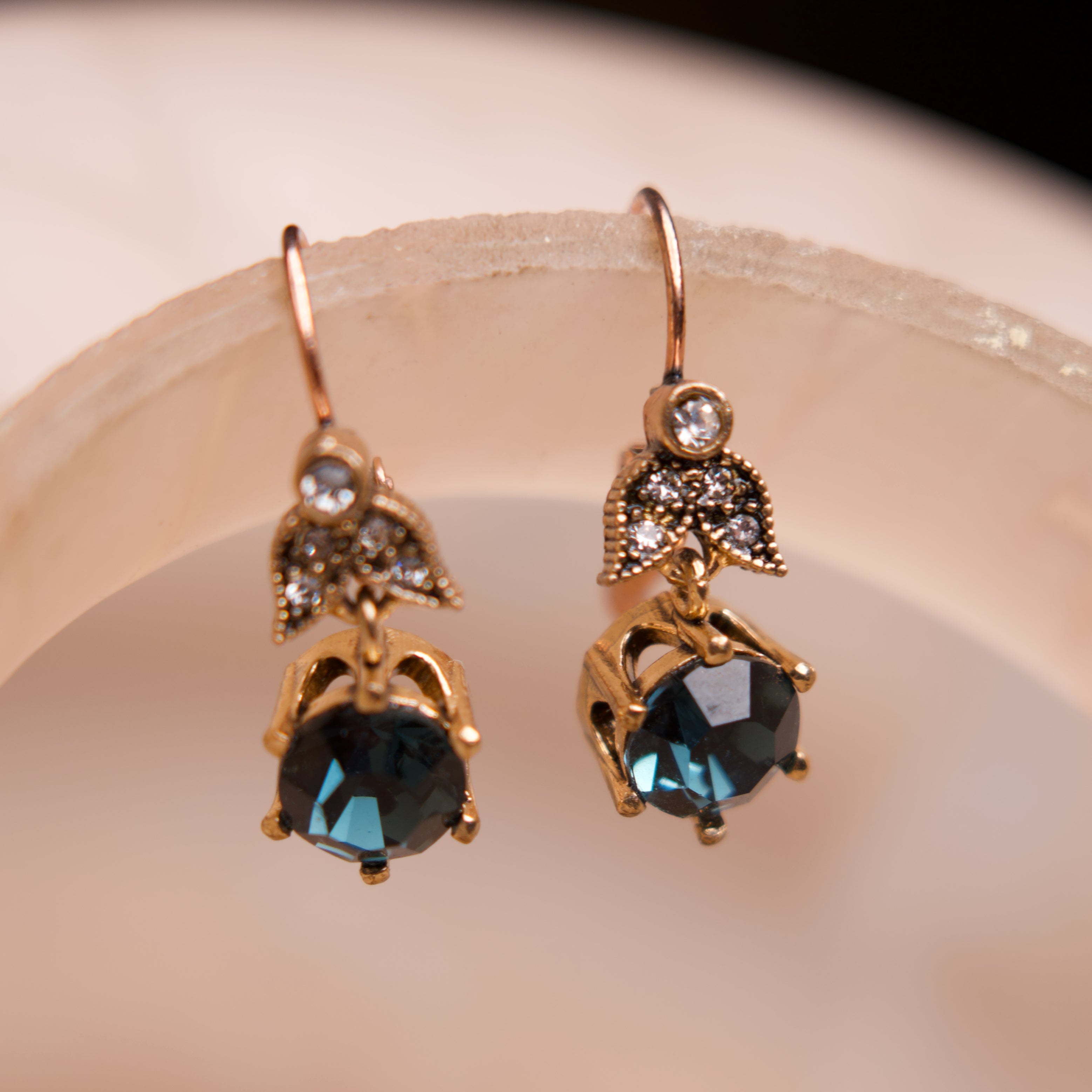 Gold earrings with black gemstones on a beige background