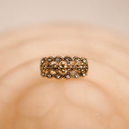Gold ring with intricate design on a beige background