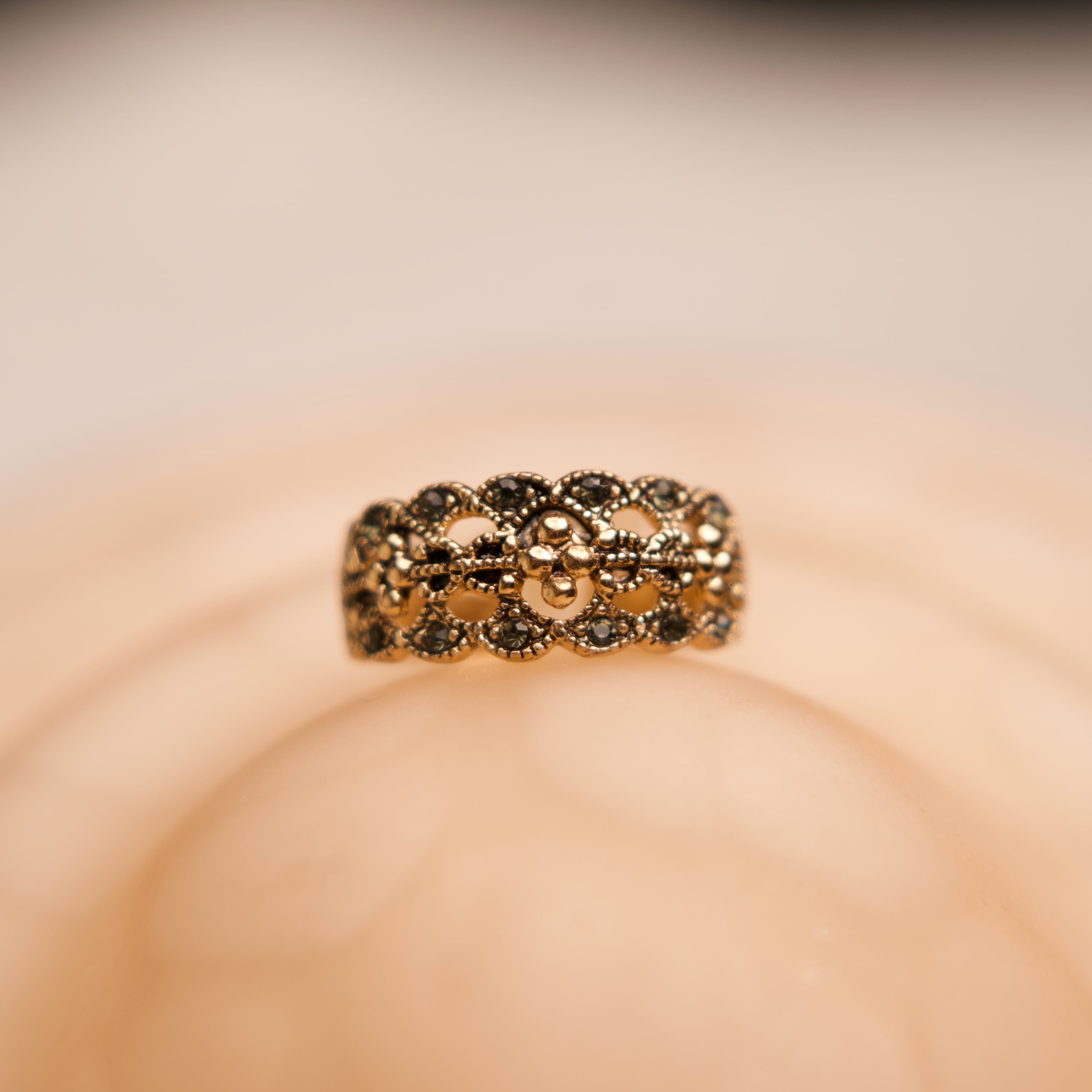 Gold ring with black stones on a beige background