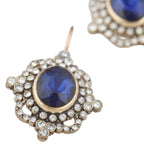 Earrings with blue gemstones and gold accents on a white background
