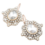 Pair of ornate earrings with clear gemstones on a white background