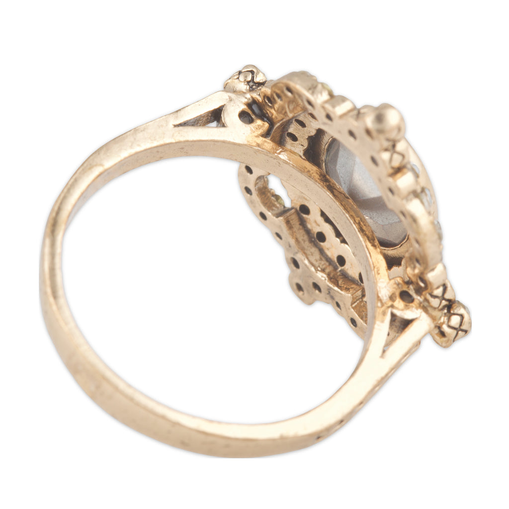 Gold ring with intricate design on a white background