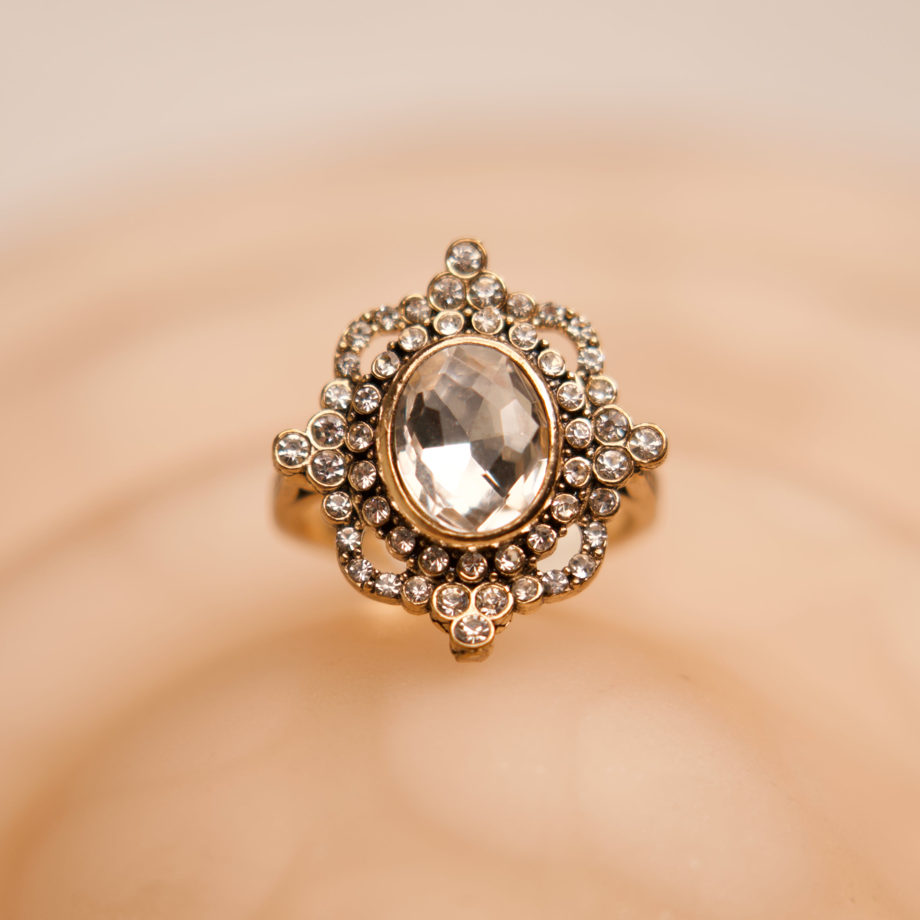 Gold ring with a central gemstone on a beige background