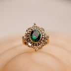 Gold ring with a green gemstone on a beige background