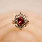 Ring with a red gemstone and gold accents on a beige background