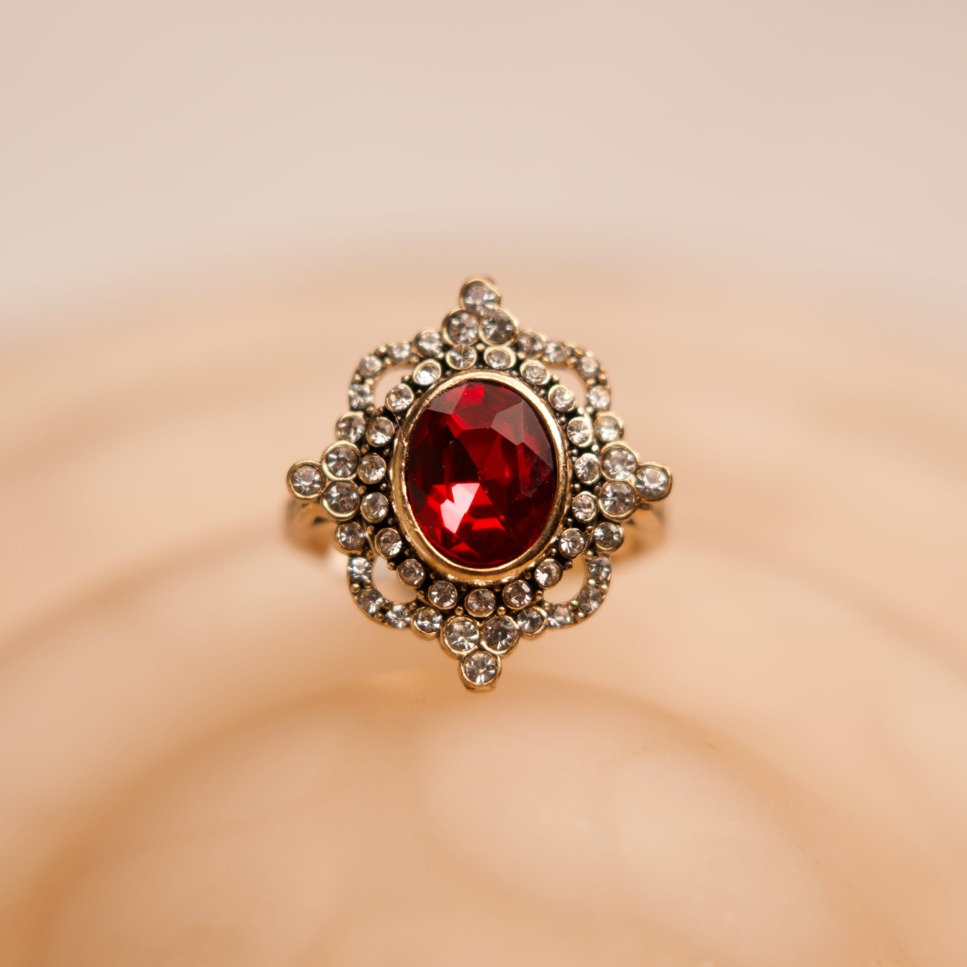Ring with a red gemstone and gold accents on a beige background