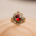 Gold ring with a red gemstone on a beige background