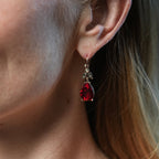 Close-up of a person wearing a red teardrop earring.