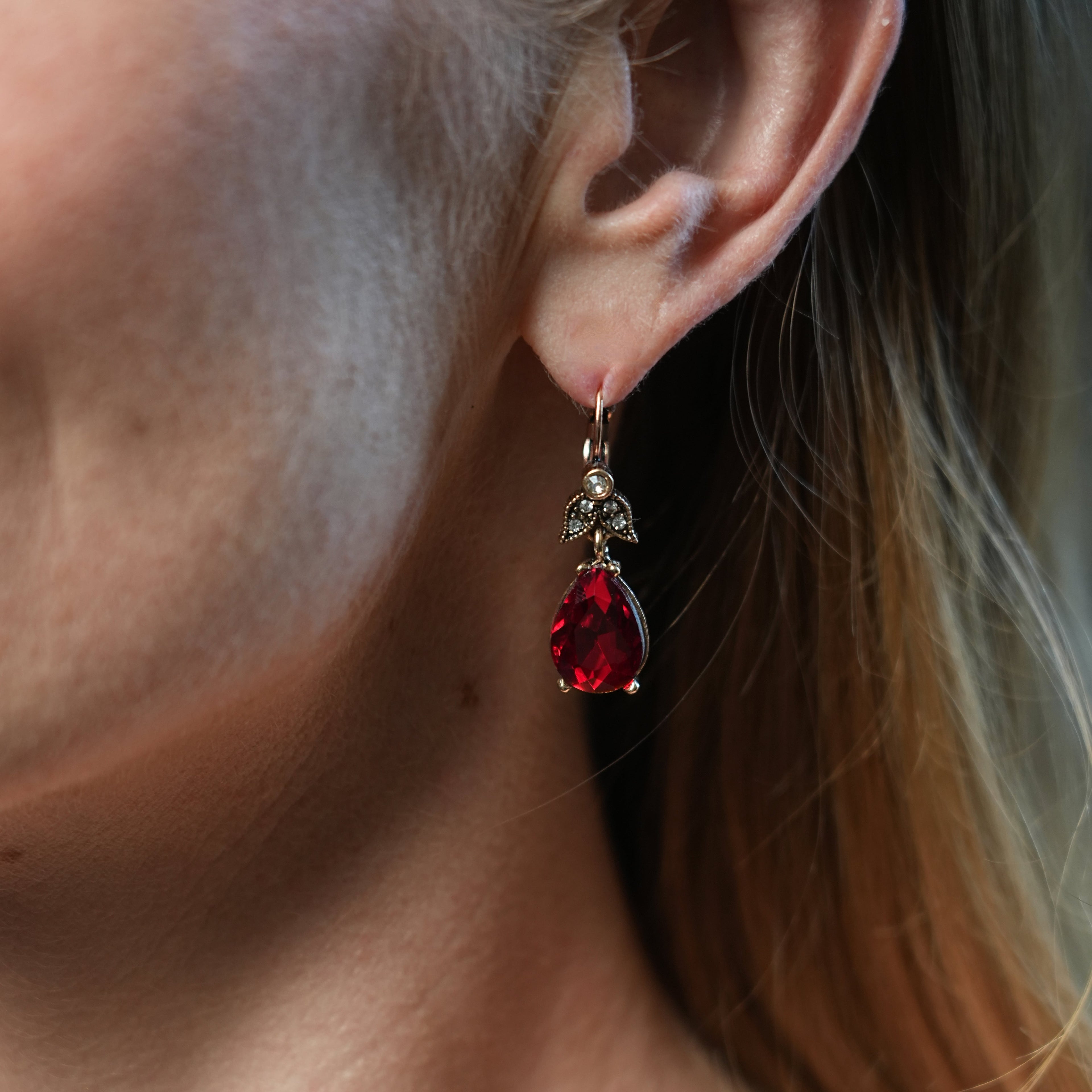 Close-up of a person wearing a red teardrop earring.