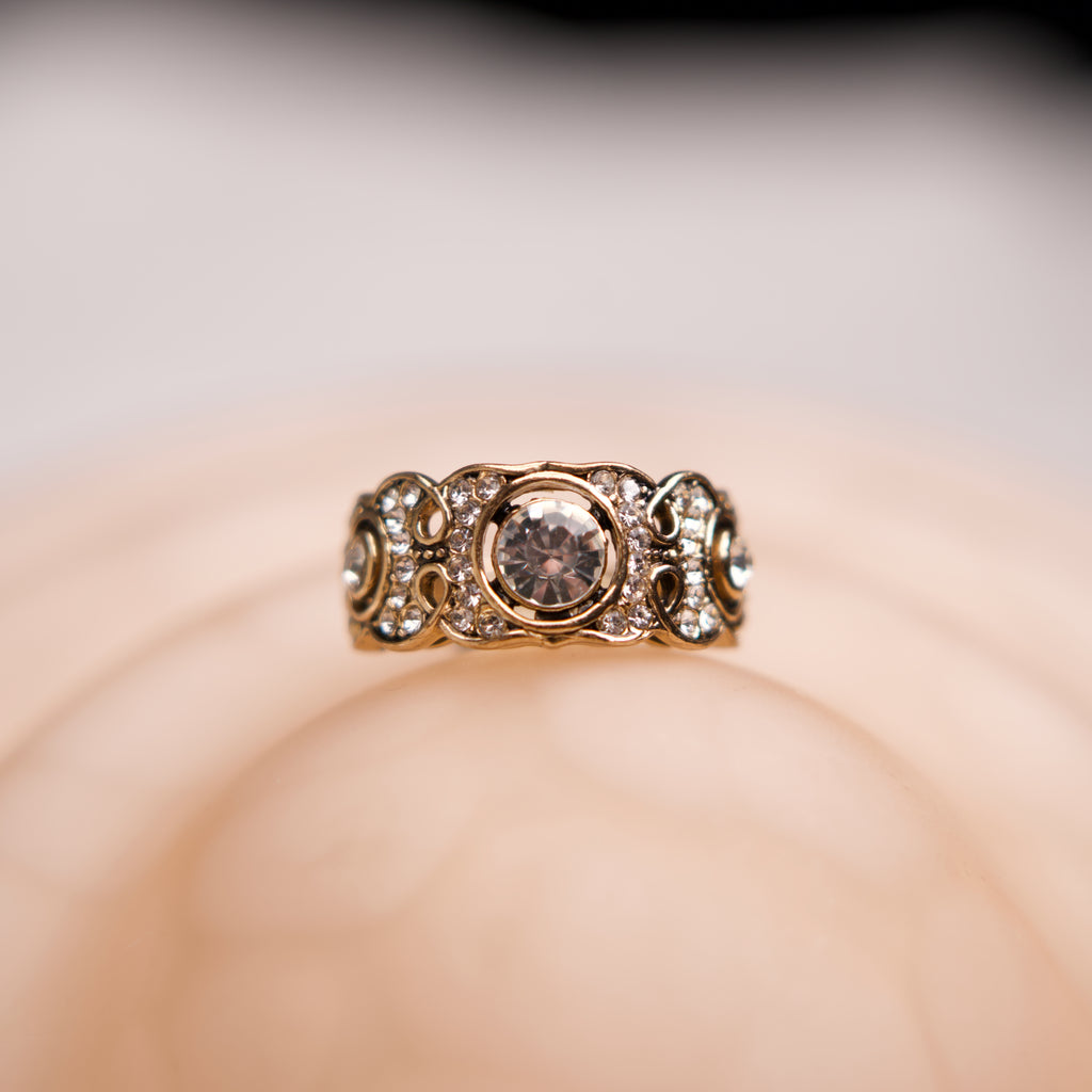 Gold ring with a central diamond on a soft beige background