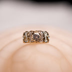 Gold ring with a central diamond on a soft beige background