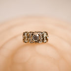 Gold ring with a central gemstone on a beige background
