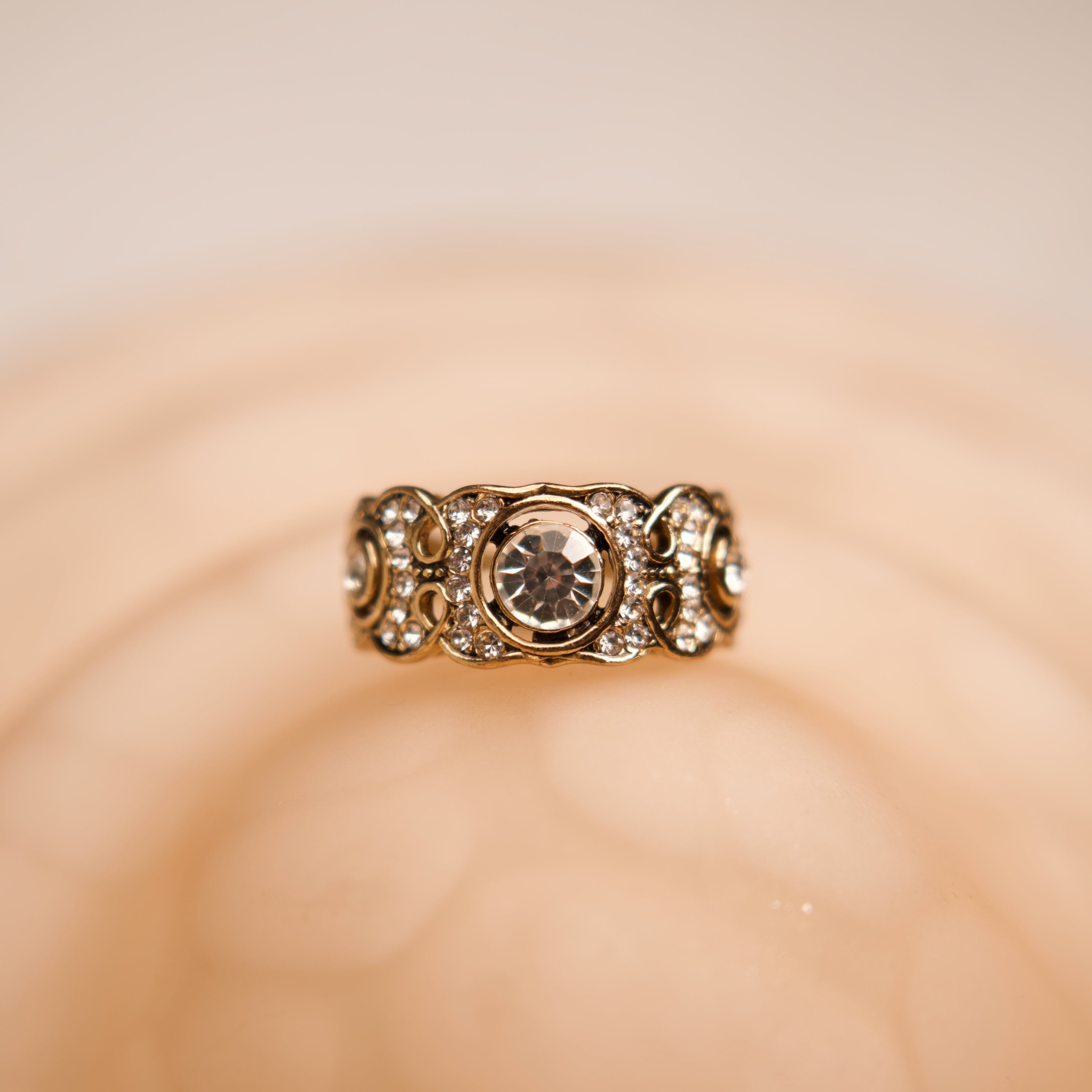 Gold ring with a central gemstone on a beige background
