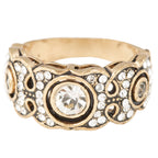 Gold ring with intricate design and clear gemstones on a white background