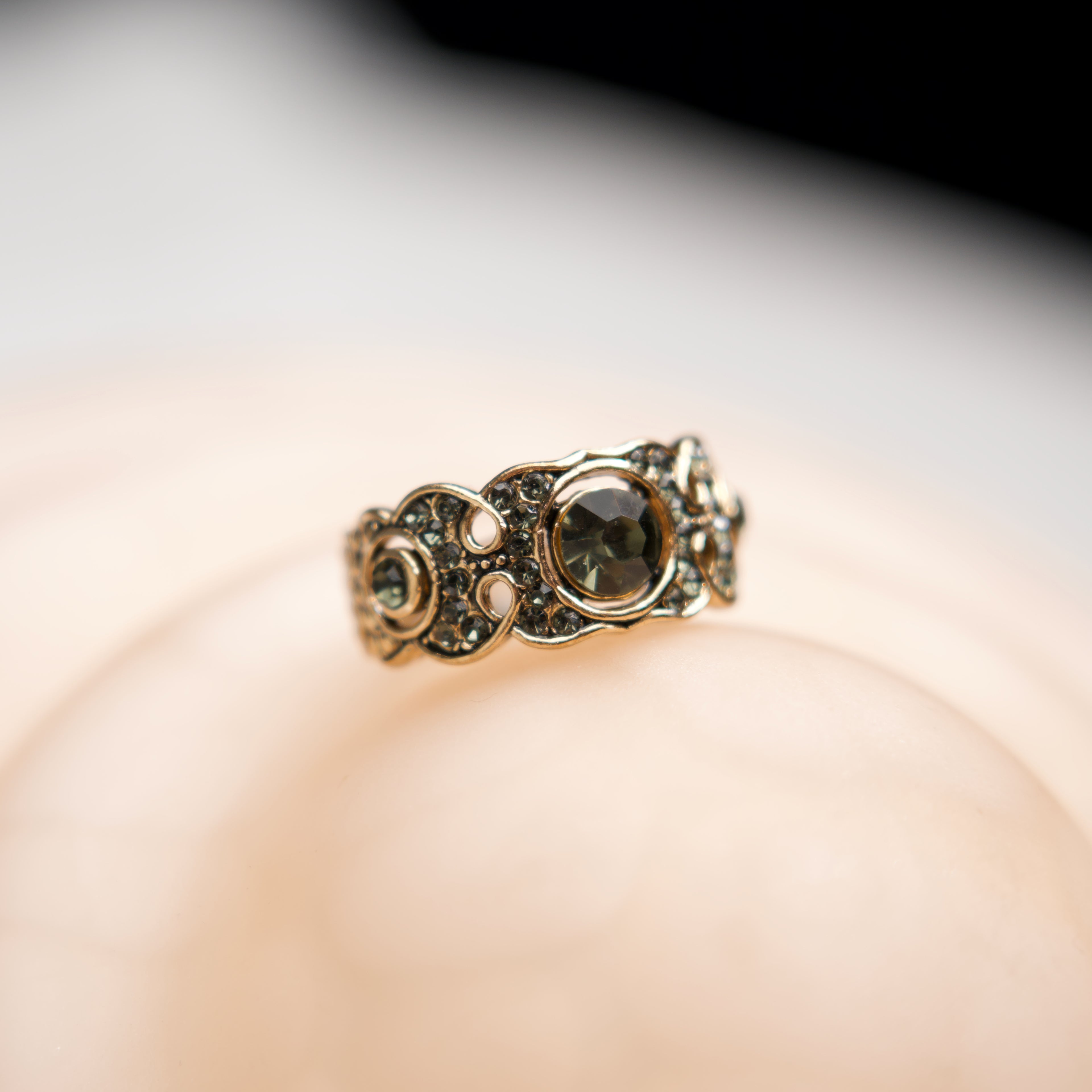 Gold ring with a central gemstone on a soft focus background