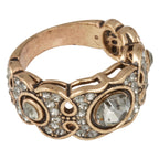 Decorative ring with rose gold band and clear gemstones on a white background