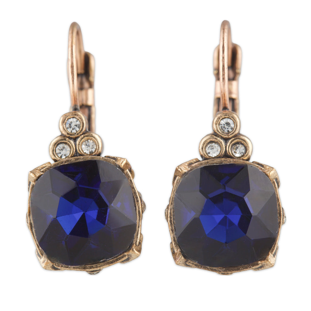 Pair of earrings with blue gemstones and rose gold accents on a white background