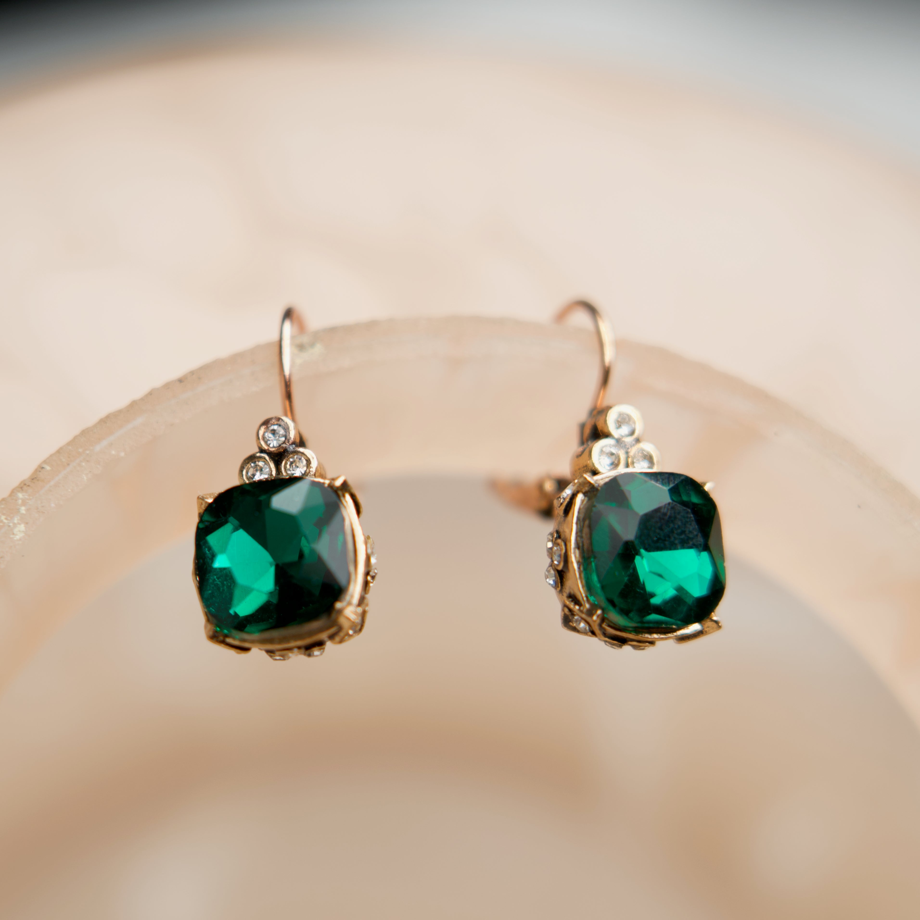 Pair of green gemstone earrings on a beige background