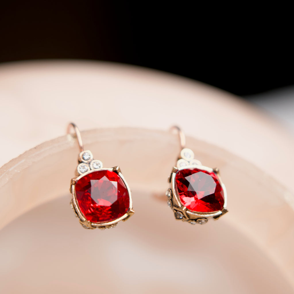 Pair of earrings with red gemstones on a light surface
