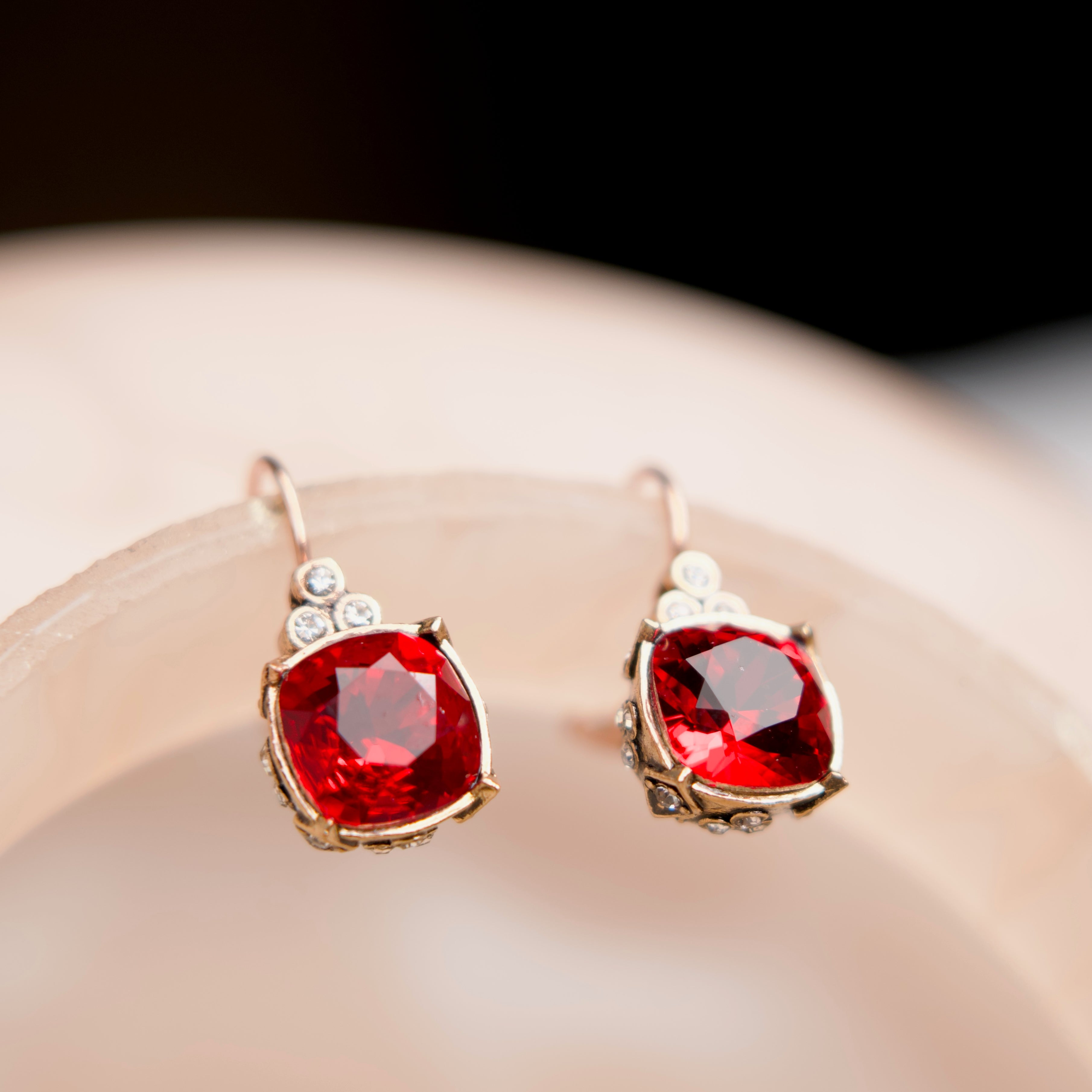 Pair of earrings with red gemstones on a light surface