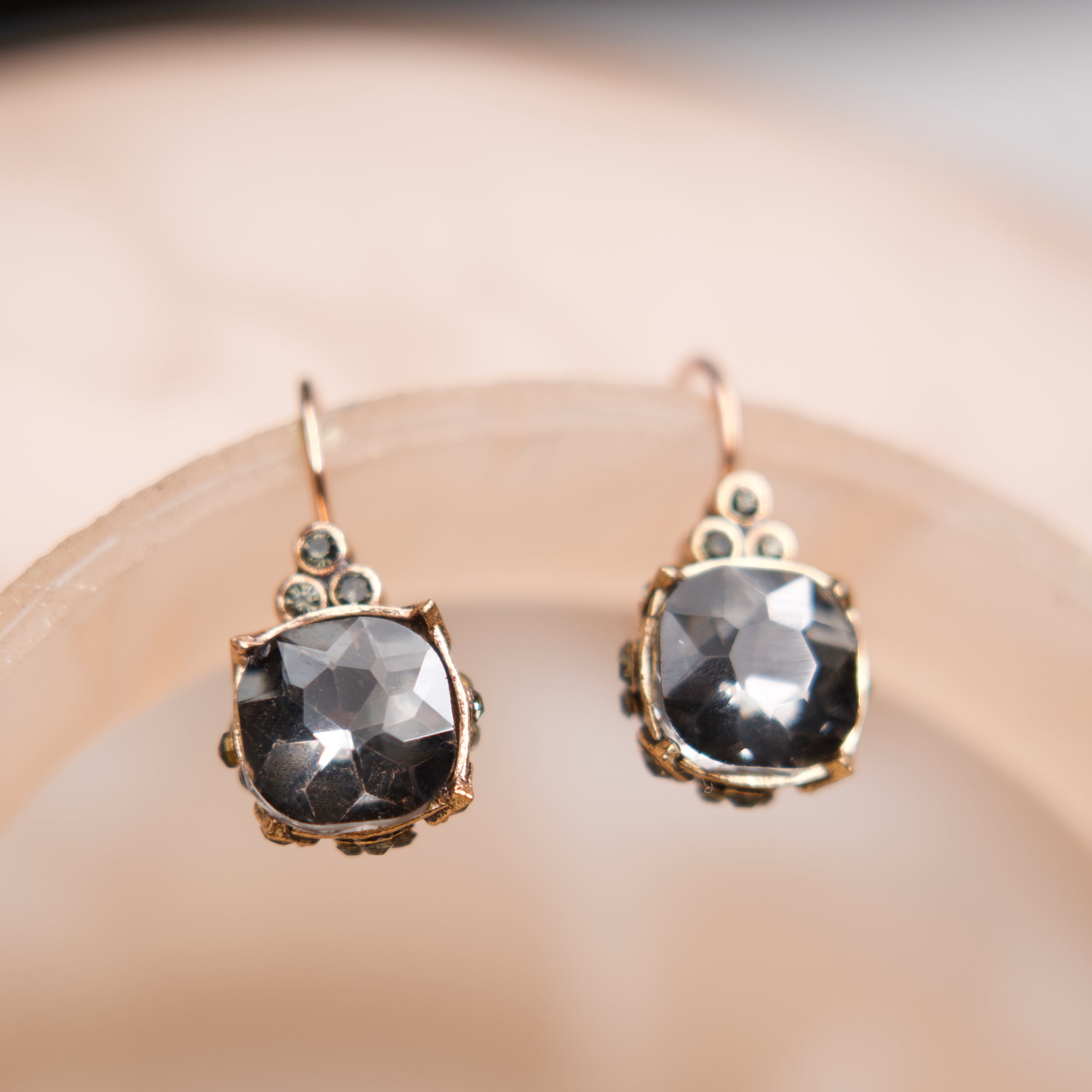 Pair of earrings with dark gemstones on a beige background