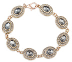 Gold bracelet with gray gemstones on a white background